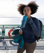 A woman sipping the straw on the brittany blue coloured 26oz Klean Kanteen rise tumbler.