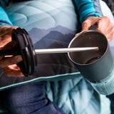 A close up of a person's hand lifting the straw lid out of a black 26oz handled Klean Kanteen rise tumbler.