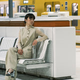 A woman sitting in on a bench in a trainstation and holding the  klean Kanteen reflect stainless steel rise bottle
