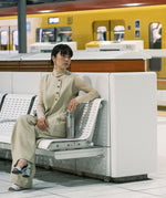 A woman sitting in on a bench in a trainstation and holding the  klean Kanteen reflect stainless steel rise bottle