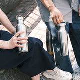 2 adults holding the klean Kanteen reflect stainless steel rise bottles showing their scale and handle detail on the loop cap
