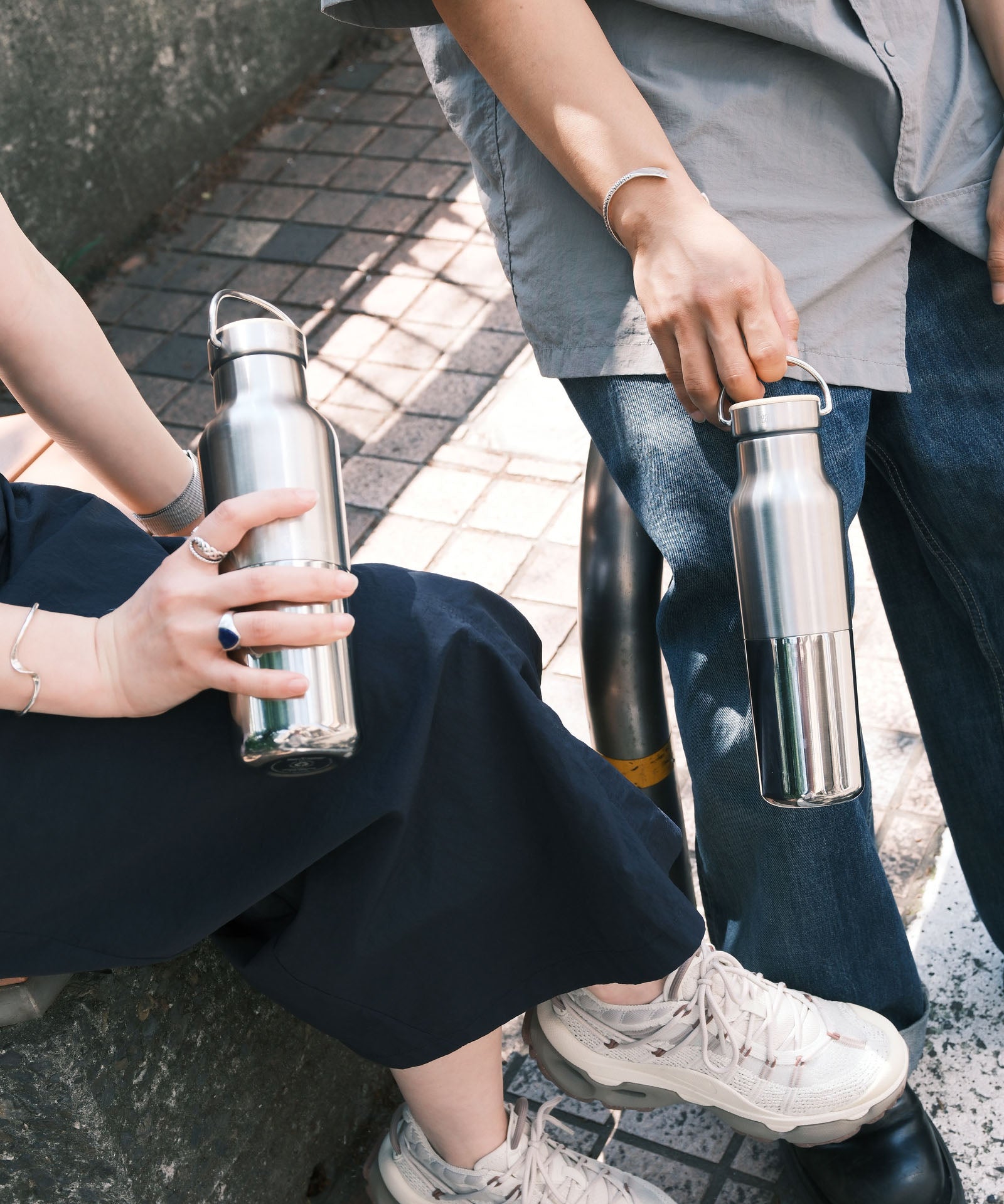 2 adults holding the klean Kanteen reflect stainless steel rise bottles showing their scale and handle detail on the loop cap