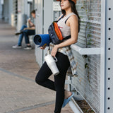 A person is seen leaning against a metal pole with fitness equipment in one hand and a tofu white coloured Klean Kanteen Limited Edition 36oz Rise Tumbler in the other