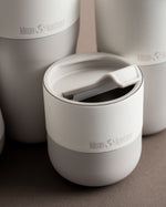 Close up of a Klean Kanteen 10oz stainless steel lowball glass in the beige colour on a brown background