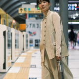 A woman standing on a platform in a train station and holding the  klean Kanteen reflect stainless steel rise bottle by the handle on the bamboo loop cap