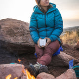 An adult sat outside by a fire