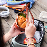 Person opening a Klean Kanteen Rise Stainless Steel Lunch Box with school bags open in the background
