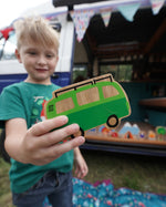 Close up of a boy holding the Lanka Kade lola campervan vehicle toy in front of a blue campervan