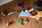 Looking down at a child playing with the Lanka Kade Babipur moel mountain toy and other dan y ser wooden toys on a wooden floor