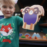Close up of a boy holding up the Lanka Kade Babipur purple ram wooden toy figure