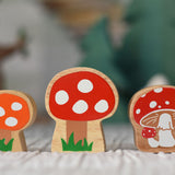 Lanka Kade and Babipur collaboration orange and red spotted toadstool and Lanka Kade Toadstool figures placed on a striped tablecloth. on