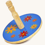 A yellow wooden Lanka Kade spinning top with red and yellow flowers on a cream background.