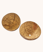 A close up of the coconut bowls from the coconut sand play set showing the 2 shells with a hole in the bottom in one shell for sand to pour through