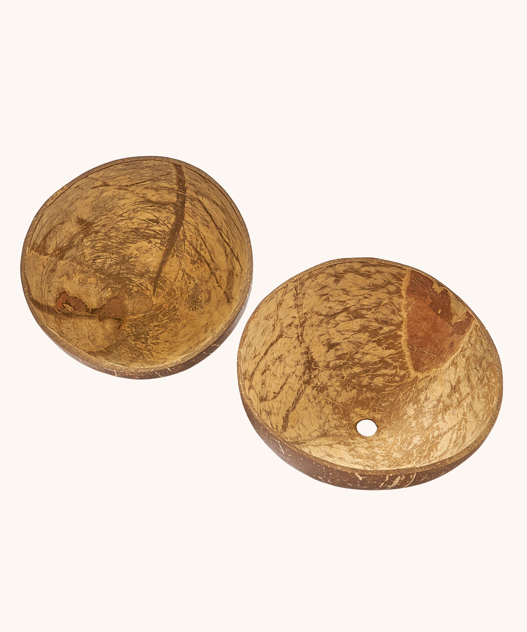 A close up of the coconut bowls from the coconut sand play set showing the 2 shells with a hole in the bottom in one shell for sand to pour through