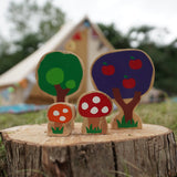 Close up of the Lanka Kade dan y ser trees and toadstool toys on a large log in front of a beige tent