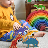 A child playing with Lanka Kade wooden toy animal figures. The child has his hand on a purple dinosaur figure. These wooden toy figures are part of a huge range of Lanka Kade fair trade, wooden toys available here at Babipur.
