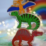 A stack of three wooden dinosaur figures from Lanka Kade. A yellow pteranodon. green iguanodon and red spinosaurus. These wooden toy figures are part of a huge range of Lanka Kade fair trade, wooden toys available here at Babipur.