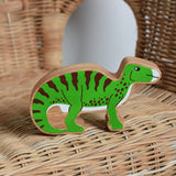 A Lanka Kade green iguanodon wooden toy figure placed on a child's wicker chair. These wooden toy figures are part of a huge range of Lanka Kade fair trade, wooden toys available here at Babipur.