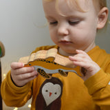 A child holding and inspecting a yellow Lanka Kade icthyosaur wooden toy figure. These wooden toy figures are part of a huge range of Lanka Kade fair trade, wooden toys available here at Babipur.