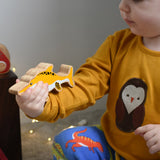 A child holding a Lanka Kade icthyosaurin their hand. These wooden toy figures are part of a huge range of Lanka Kade fair trade, wooden toys available here at Babipur.