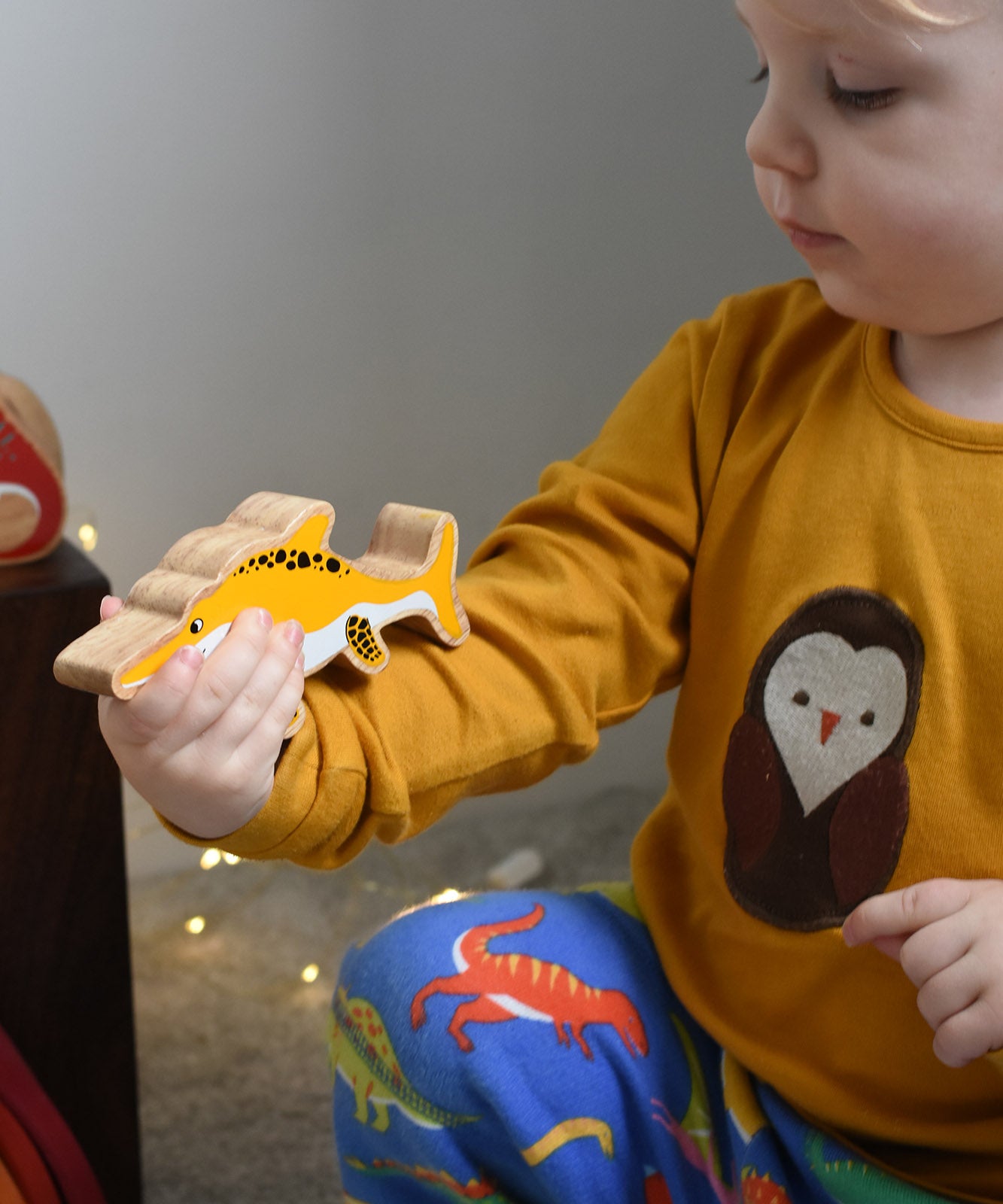 A child holding a Lanka Kade icthyosaurin their hand. These wooden toy figures are part of a huge range of Lanka Kade fair trade, wooden toys available here at Babipur.