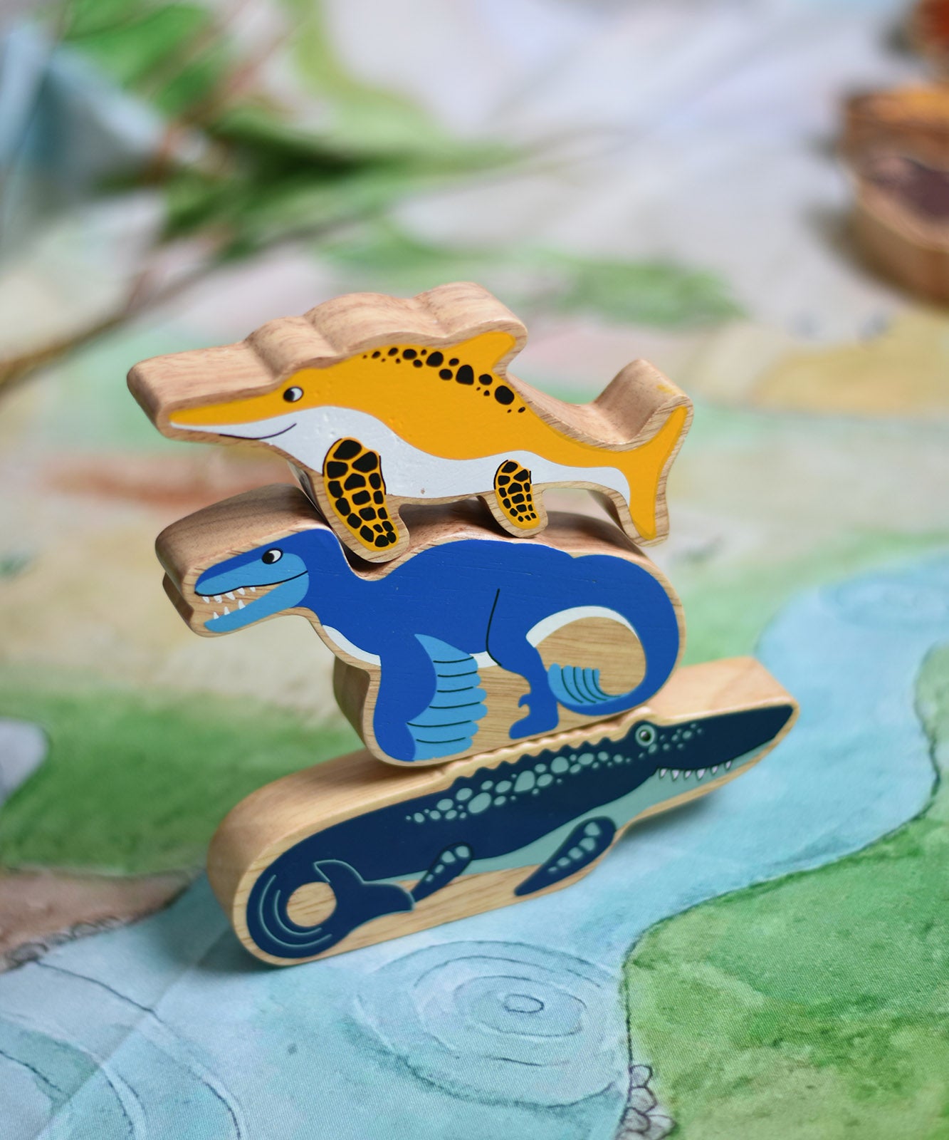 A stack of Lanka Kade toy figures with the icthyosaur placed on top of a utahraptor and mososaurus. These wooden toy figures are part of a huge range of Lanka Kade fair trade, wooden toys available here at Babipur.