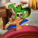A close up of a child's hand holding the Lanka Kade green iguanodon wooden toy figure, placing it on a pteranodon figure. These wooden toy figures are part of a huge range of Lanka Kade fair trade, wooden toys available here at Babipur.
