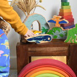 A child playing with Lanka Kade wooden toy dinosaur figures. The child is holding the ichthyosaur in their hand. These wooden toy figures are part of a huge range of Lanka Kade fair trade, wooden toys available here at Babipur.