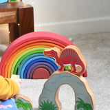 The Lanka Kade Wooden red Spinosaurus Dinosaur figure placed on a Lanka Kade cave from the prehistoric playset. These wooden toy figures are part of a huge range of Lanka Kade fair trade, wooden toys available here at Babipur.