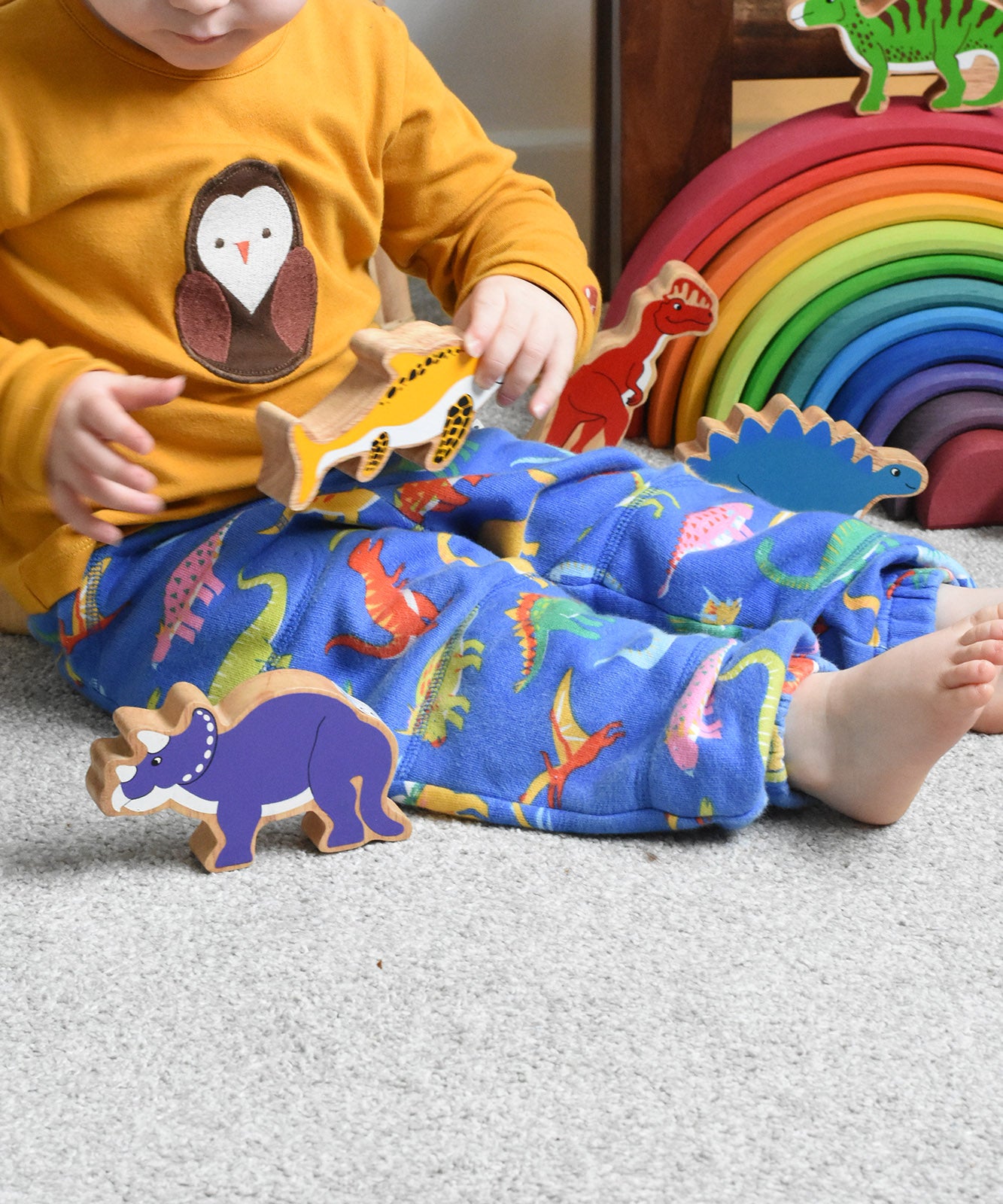A child playing with Lanka Kade wooden toy dinosaur figures. These wooden toy figures are part of a huge range of Lanka Kade fair trade, wooden toys available here at Babipur.