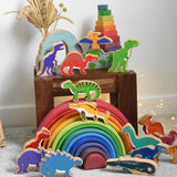 A collection of wooden dinosaur figures from Lanka Kade place on a small wooden table and Grimm's rainbow. These wooden toy figures are part of a huge range of Lanka Kade fair trade, wooden toys available here at Babipur.