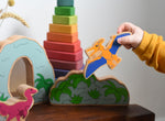 A child playing with Lanka Kade wooden toy dinosaur figures. The child is holding the Lanka Kade pteranodon figure in their hand and flying it through the air. These wooden toy figures are part of a huge range of Lanka Kade fair trade, wooden toys available here at Babipur.