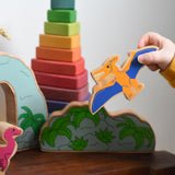 A child playing with Lanka Kade wooden toy dinosaur figures. The child is holding the Lanka Kade pteranodon figure in their hand and flying it through the air. These wooden toy figures are part of a huge range of Lanka Kade fair trade, wooden toys available here at Babipur.