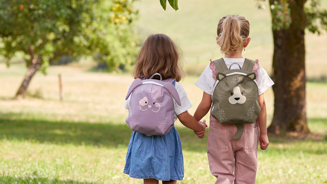 Two children holding hands and wearing the Lassig About Friends animal backpacks.