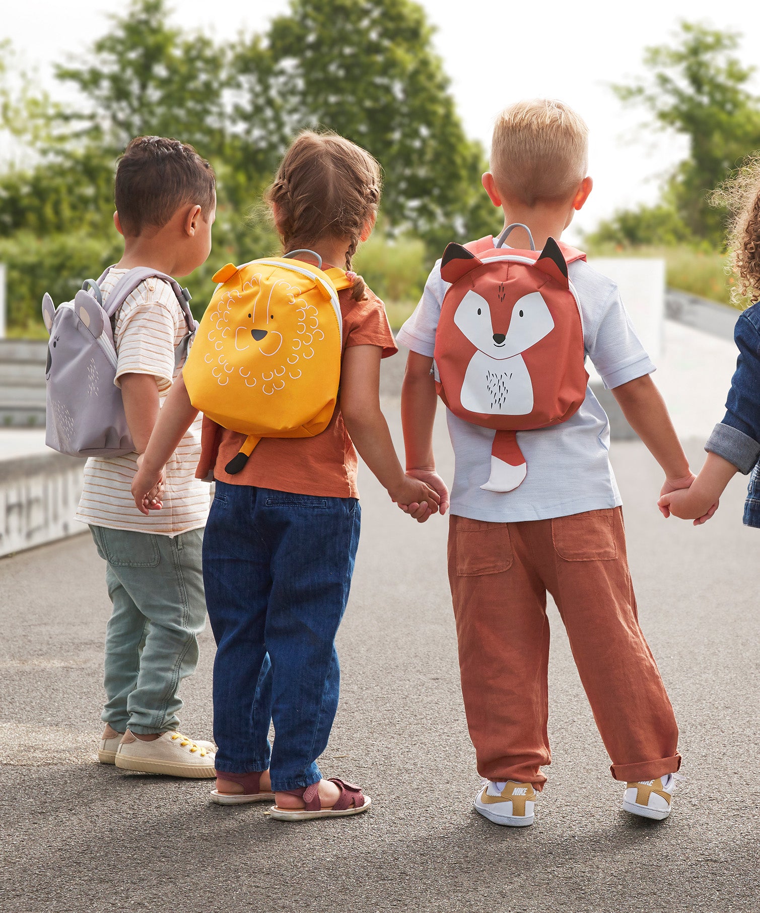 Children holding hands, all wearing Lassig 'About Friends' tiny ids backpacks with different animal styles.