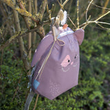 Lassig kids tiny bunny backpack hanging on a tree by the loop handle on the top with decorative reeds clipped on by a peg
