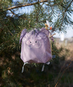 Lassig kids tiny bunny backpack hanging on a tree by the loop handle on the top with decorative reeds clipped on the ear by a peg