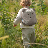 A child walking through a grassy gfield and wearing the Lassig kids tiny dragon backpack