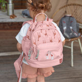 A little girl wearing the Lassig kids mini backpack in a Safari Giraffe pink print.