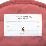 A closeup of the 'pass-me-on' name label inside the Lassig Kids mini backpack, with multiple spaces for kids to hand the bag down to younger siblings