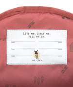 A closeup of the 'pass-me-on' name label inside the Lassig Kids mini backpack, with multiple spaces for kids to hand the bag down to younger siblings