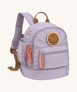 The Lassig mini kids backpack in a lilac colour with orange zips and a smiley face patch.