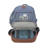 The Lassig mini backpack in blue with a tractor on the front, with the bottom zip opened so you can see the opened bottom compartment, which is storing a lunch box.