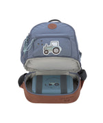 The Lassig mini backpack in blue with a tractor on the front, with the bottom zip opened so you can see the opened bottom compartment, which is storing a lunch box.