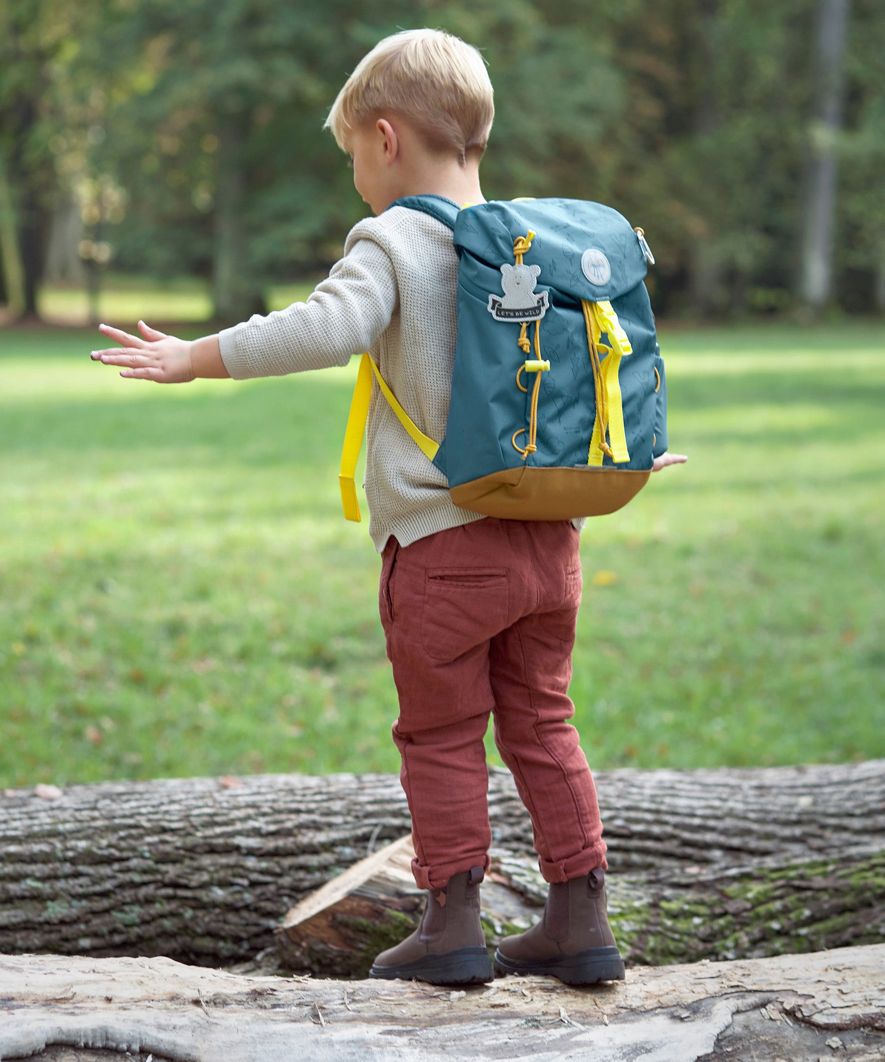 A little boy wearing the Lassig kids mini outdoor backpack in Adventure Blue.