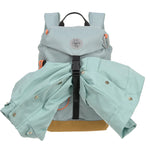 The Lassig kids mini outdoor backpack in blue, with a coat secured under the front strap.