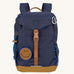 The Lassig kids mini outdoor backpack in navy blue, with a brown strap and buckle, and a smiley face patch.