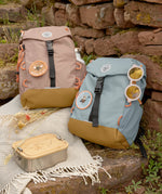 Two Lassig kids mini outdoor backpacks, one in hazelnut brown and another in light blue.