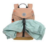 The Lassig kids mini outdoor backpack in a hazelnut light brown colour, with a coat secured in the front strap.