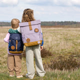 Two children wearing Lassig kids backpacks in a field.